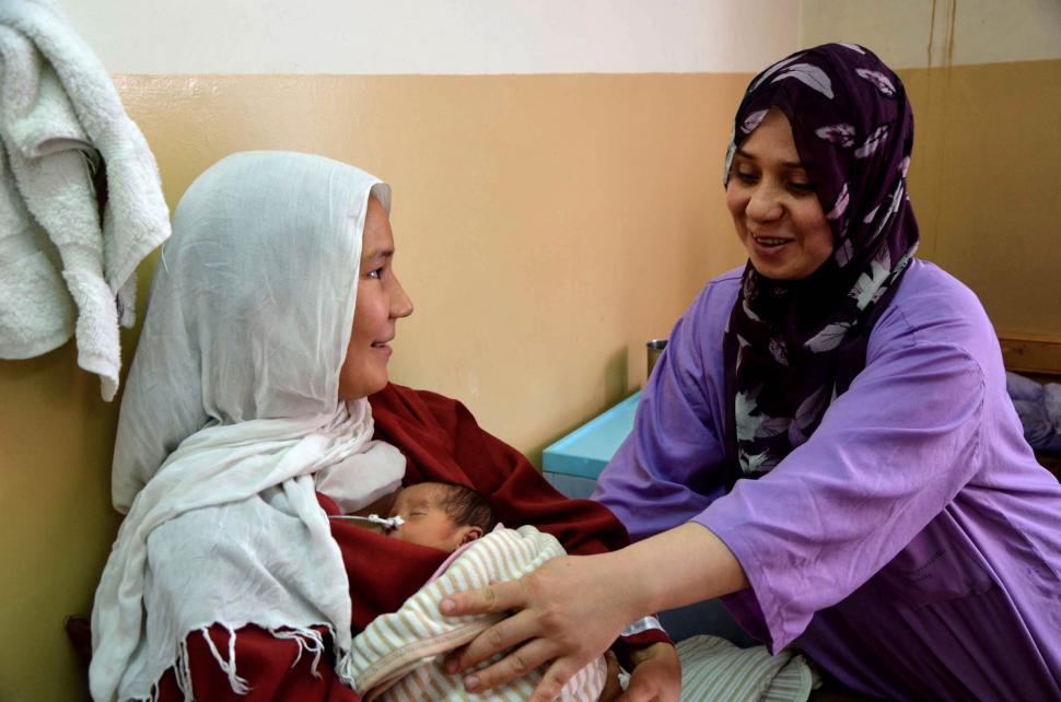 Een verloskundige in het Dasht-e-Barchi-ziekenhuis in Kabul, Afghanistan, helpt een moeder bij geven van kangoeroezorg aan haar pasgeboren kind.