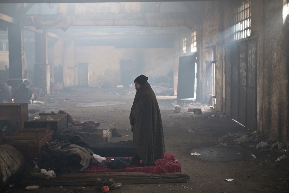 Un homme se trouve au milieu de l'entrepôt utilisée comme abri par des réfugiés à Belgrade