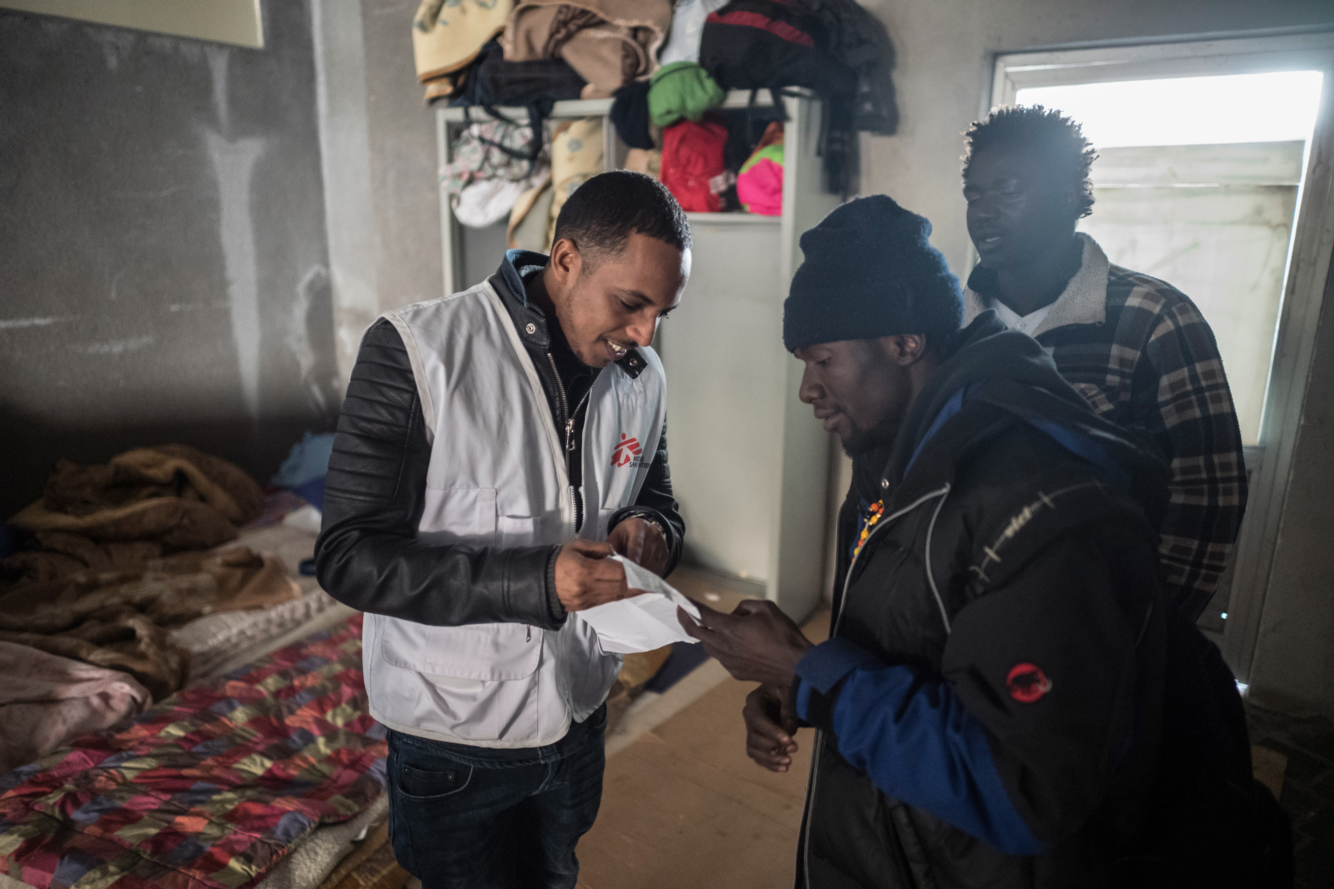 Cultureel mediator Aron Berhane praat met Alaji uit Gambia en Diere uit Senegal, in Como. © 