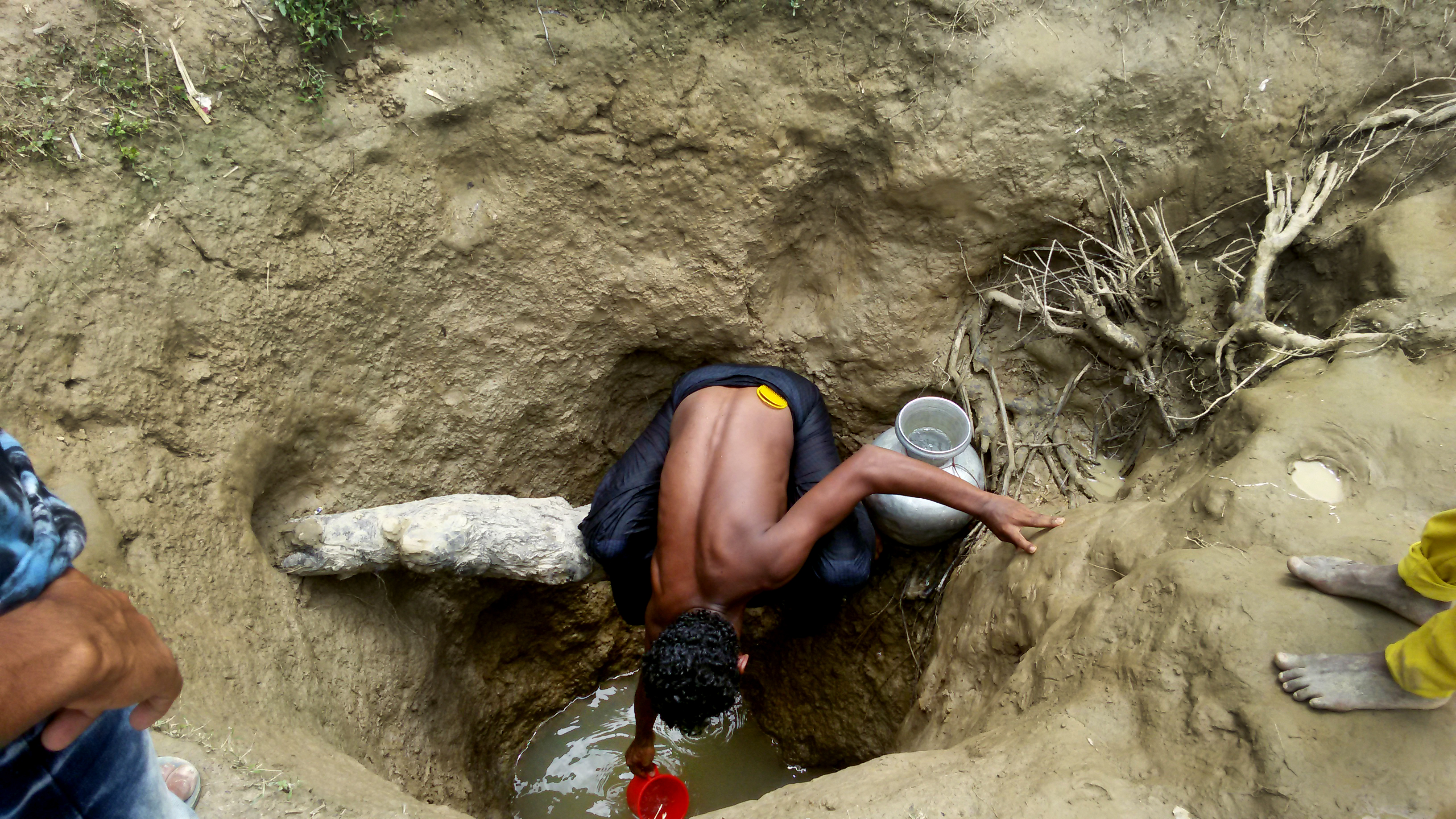 Un homme récupère l'eau d'un puits creusé à la main dans un camp de fortune d'Unchiparang.
