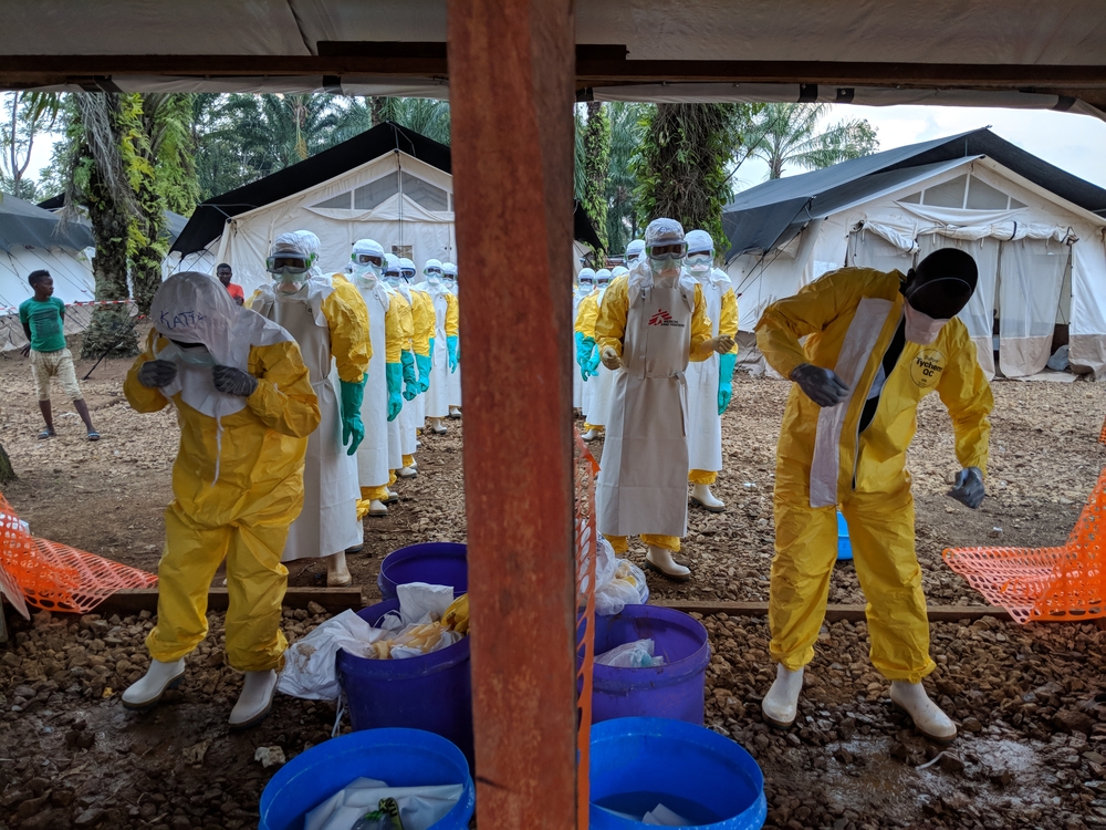 Une équipe retire son équipement de protection individuelle après avoir monté une tente dans la zone de haut risque dans le Centre de traitement Ebola. C’est un travail difficile à faire avec l’équipement de protection.