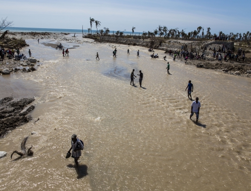 Haïtianen stappen door het water na de doortocht van de orkaan Matthew. © Andrew McConnell/Panos Pictures